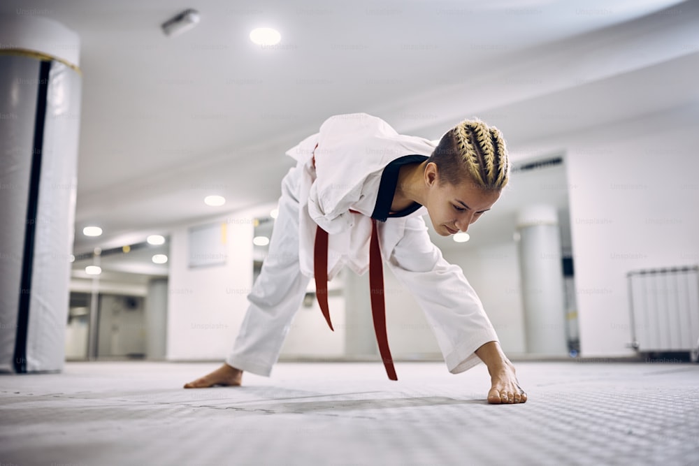Mujer atlética con para-habilidad estirándose mientras calienta para el entrenamiento de taekwondo en el gimnasio.