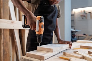 Cropped portrait of young black boy in carpentry workshop using power drill
