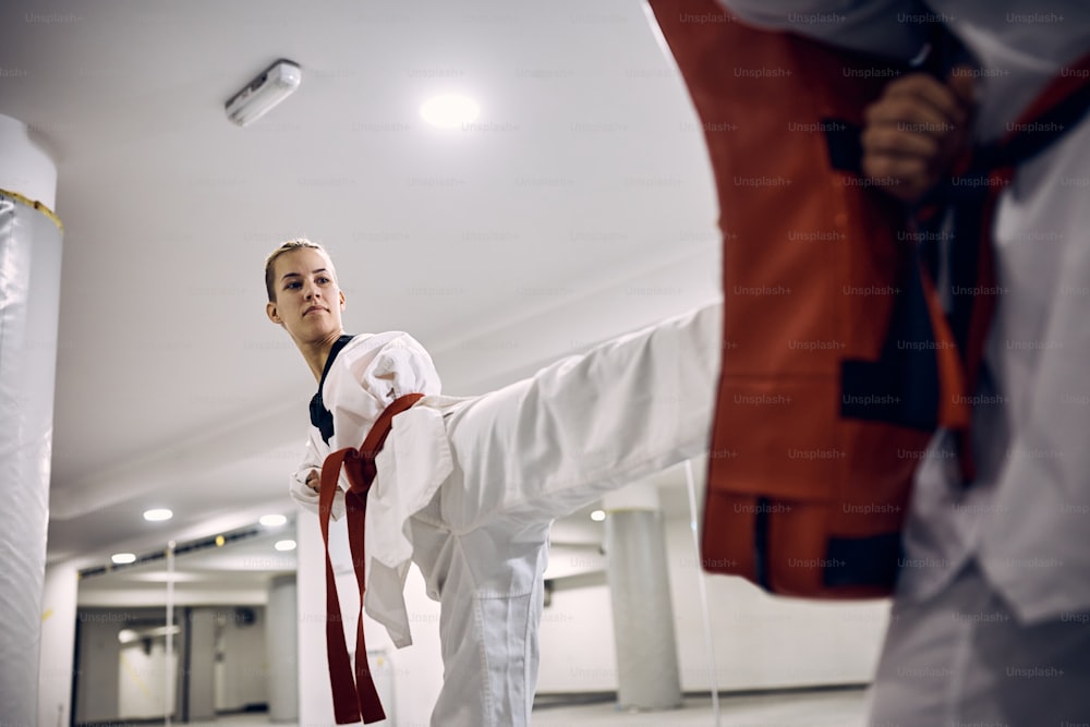 ヘルスクラブでのテコンドーのトレーニング中にインストラクターと脚の蹴りを練習する障害のある女性武道家。