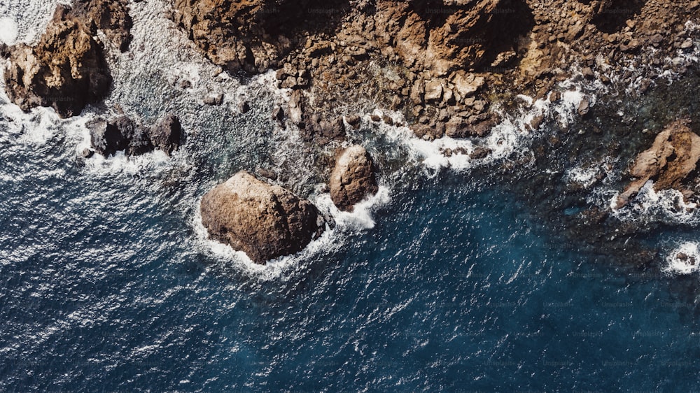 Vue verticale ci-dessus de l’eau bleue et des rochers du littoral. Paysage de mer de la nature du drone. Paysage au-dessus de la mer avec des vagues et de l’eau claire transparente