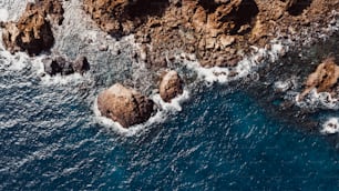 Above vertical view of blue water and rocks coastline. Nature sea landscape from drone. Above seascape with waves and transparent clean water