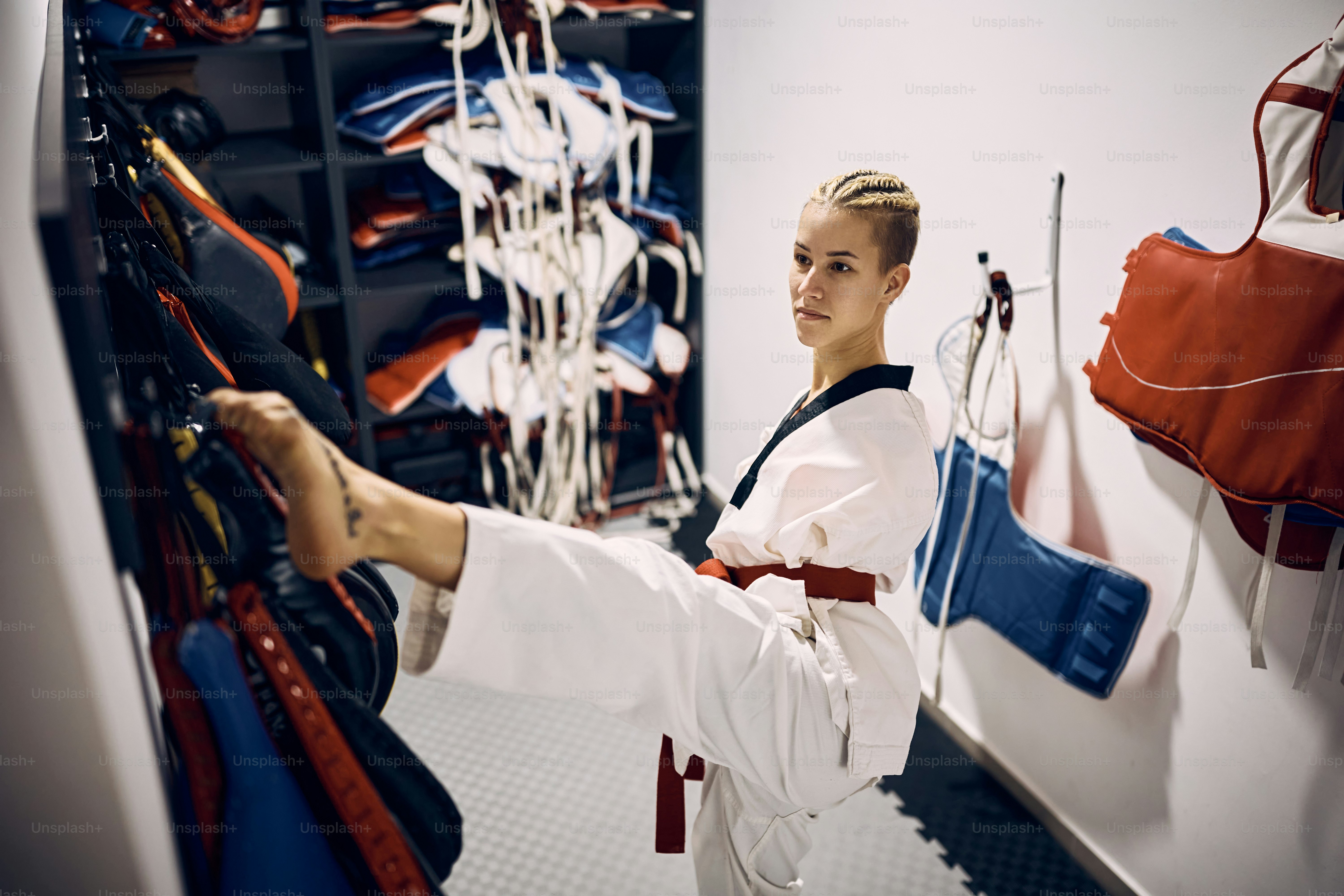 Luchadora de taekwondo con para-habilidad usando sus piernas mientras se viste en el camerino del club de artes marciales.