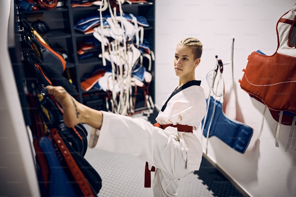 Taekwondo fighter with para-ability using her legs while getting dressed in dressing room at martial arts club.