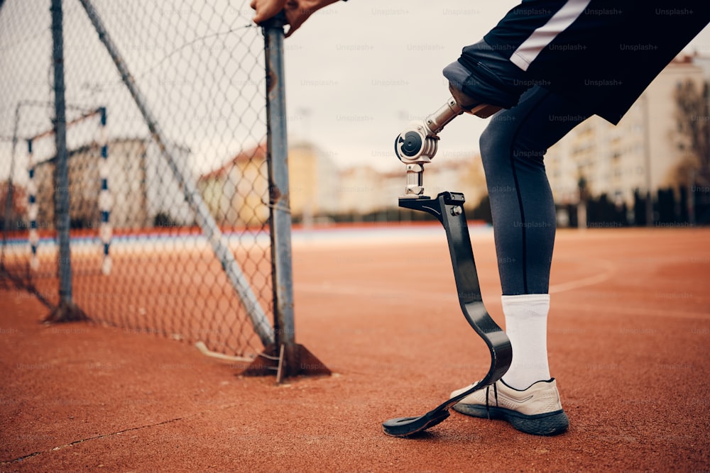 Close-up de homem atlético com uma perna protética durante o treinamento esportivo no estádio.