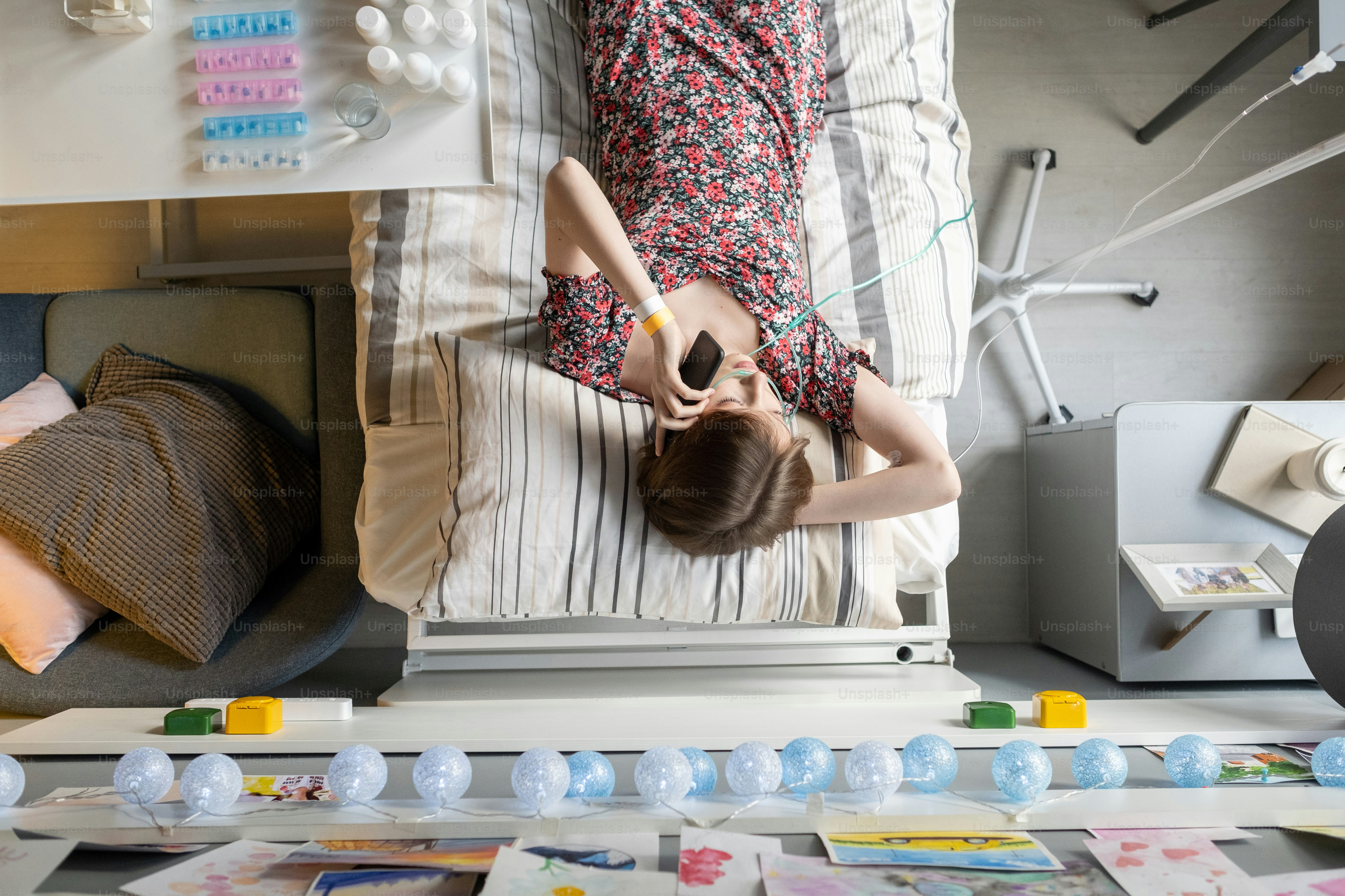 High angle view of sick woman having a conversation on mobile phone while resting on the bed at hospital ward