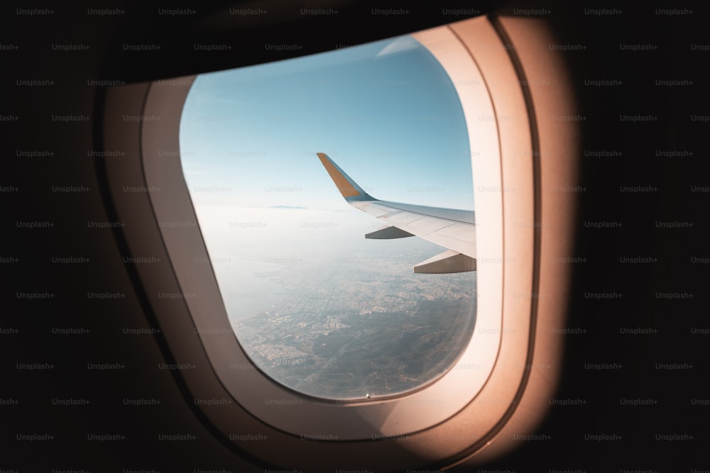 雲の霞の中の美しいテッサロニキの街を見下ろす翼の飛行機の窓からの眺め