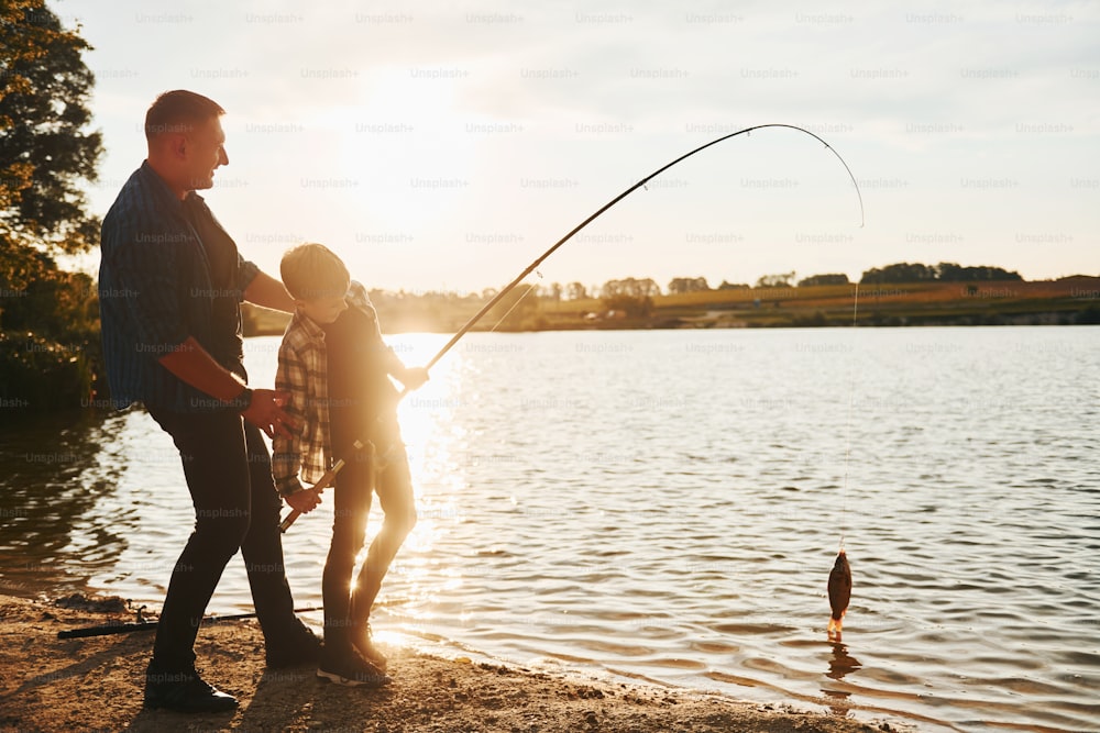 Conception of hobbies. Father and son on fishing together outdoors at summertime.