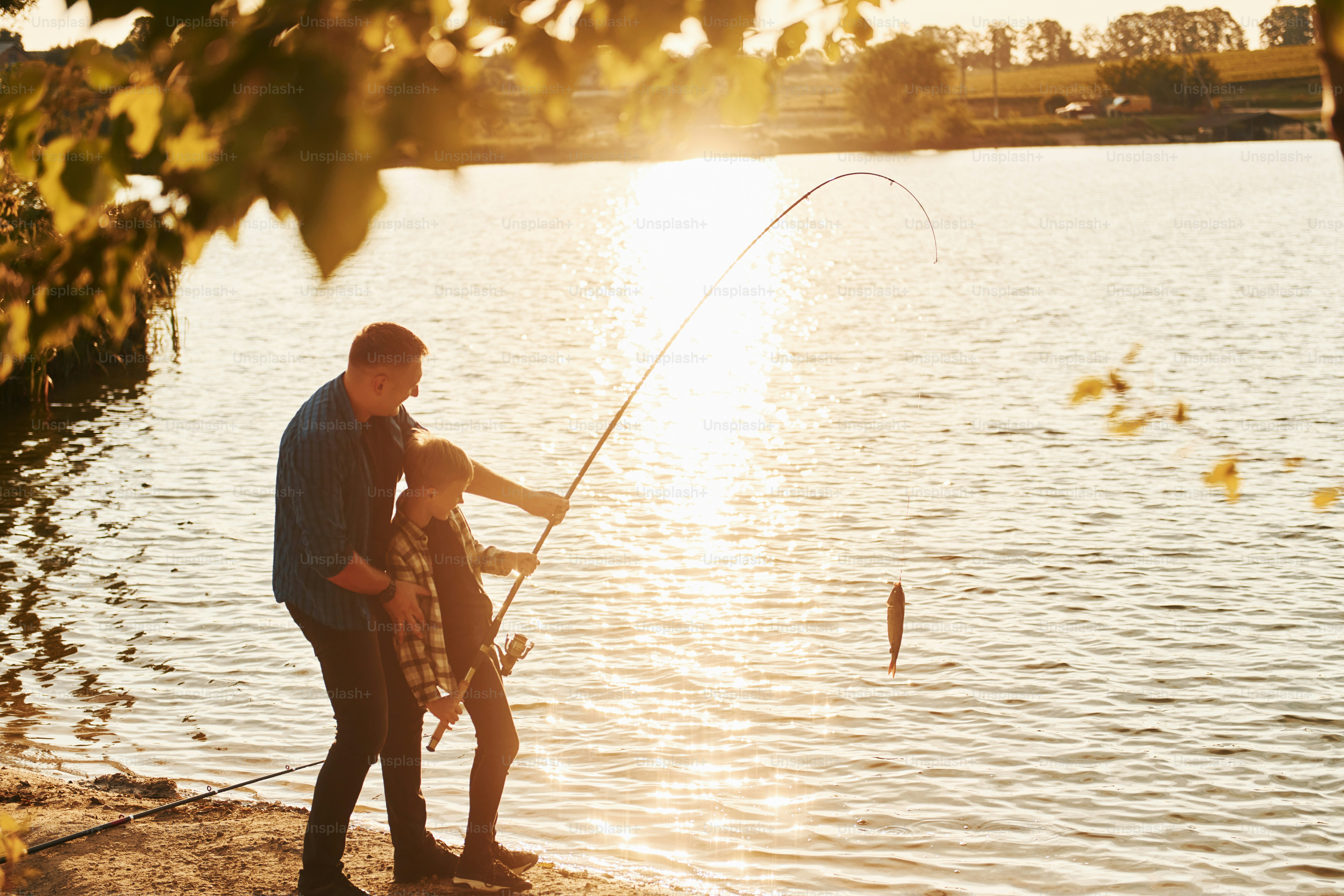 With catch. Father and son on fishing together outdoors at summertime.