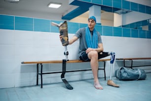 Un jeune amputé change sa prothèse de jambe alors qu’il se prépare pour l’entraînement de natation dans le vestiaire.