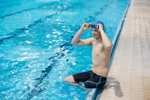 실내 수영장에서 스포츠 훈련을 하는 젊은 행복한 절단 환자.