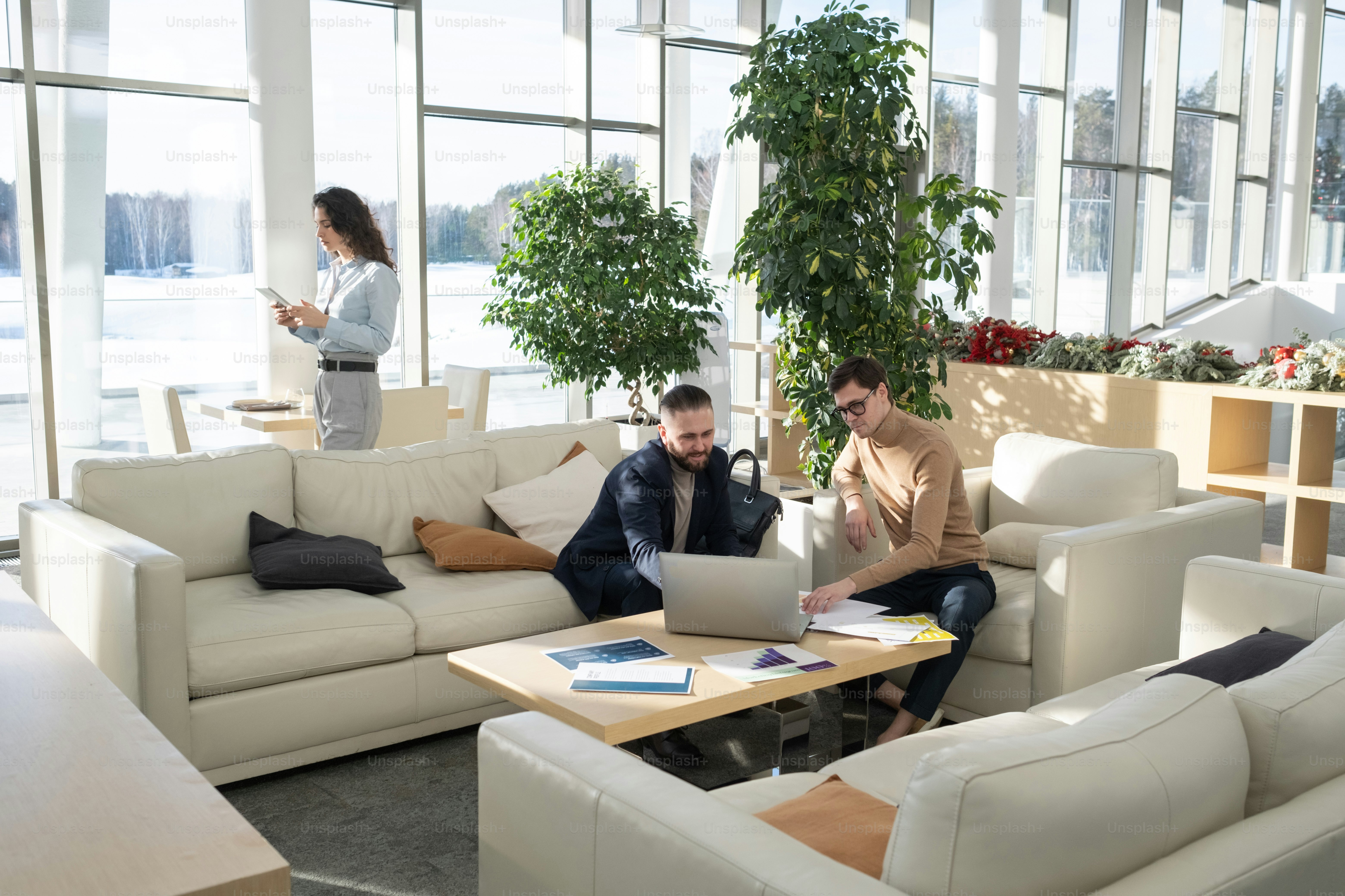 Dois empresários confiantes sentados à mesa na frente do laptop enquanto discutem dados on-line e novas estratégias de negócios na reunião