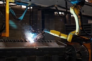 機械製造工場内の修理工程における巨大鉄産業用自動機械の一部へのアーク溶接