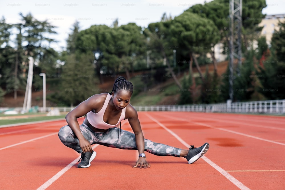 Stock photo of an African-American sprinter stretching her legs before training