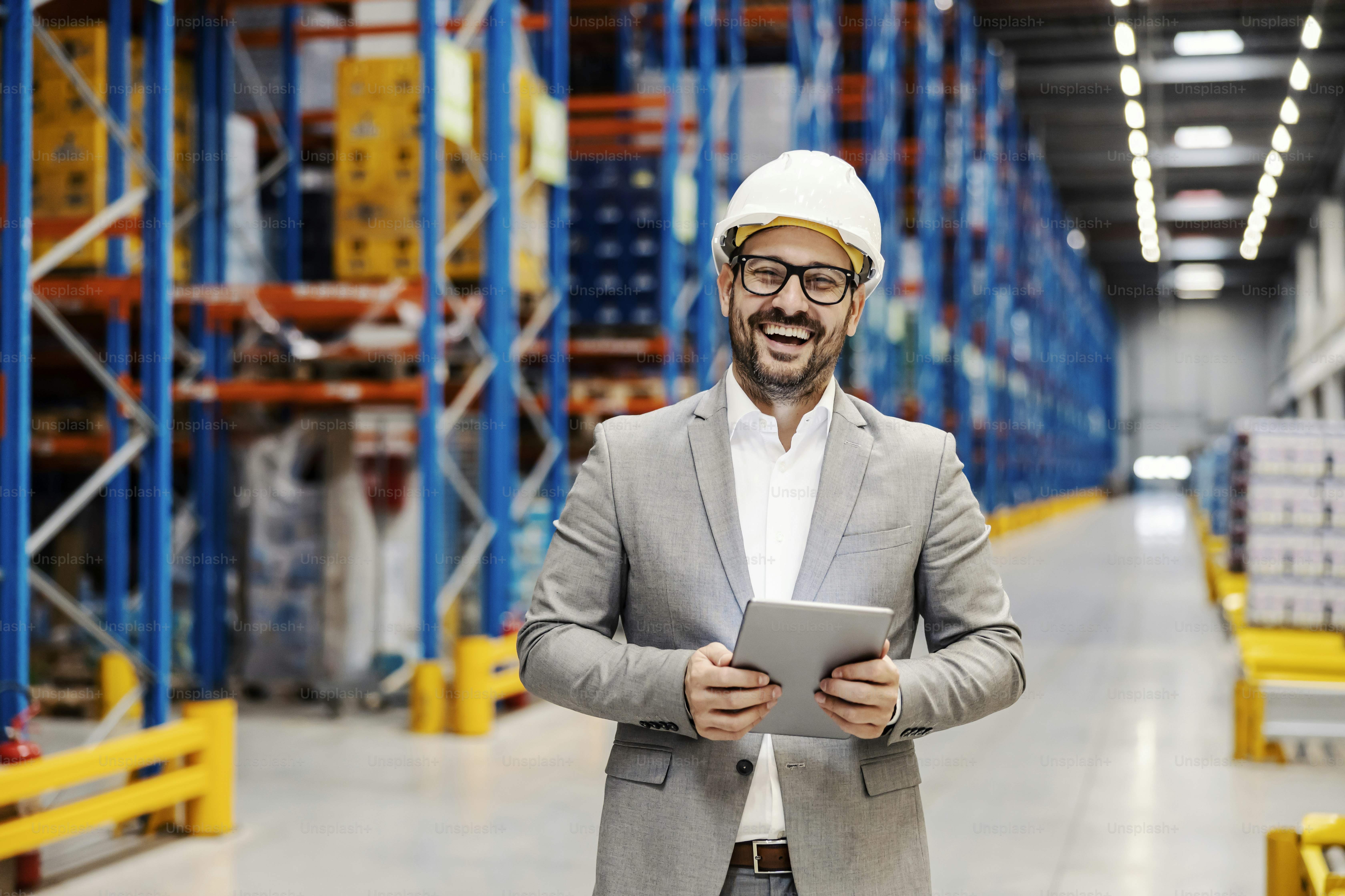 A smiling inspector holding tablet in storage and looking at the camera.