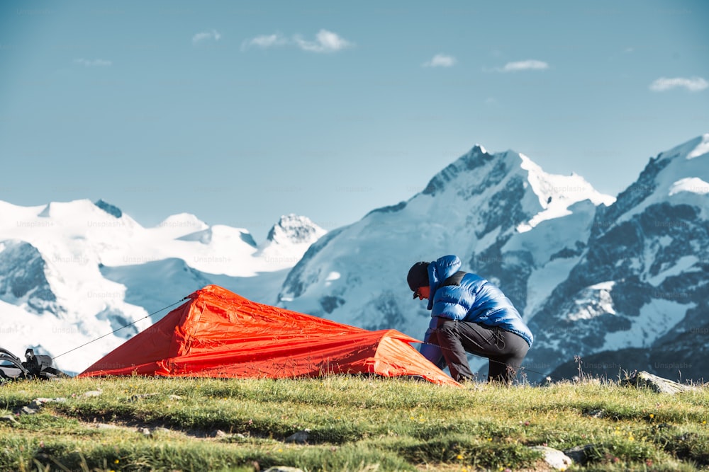 A man adventurer sets up his tent in the high mountains