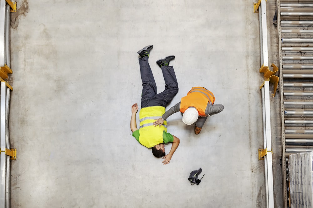 Top view of inspector finding an injured unconscious storage worker laying down.