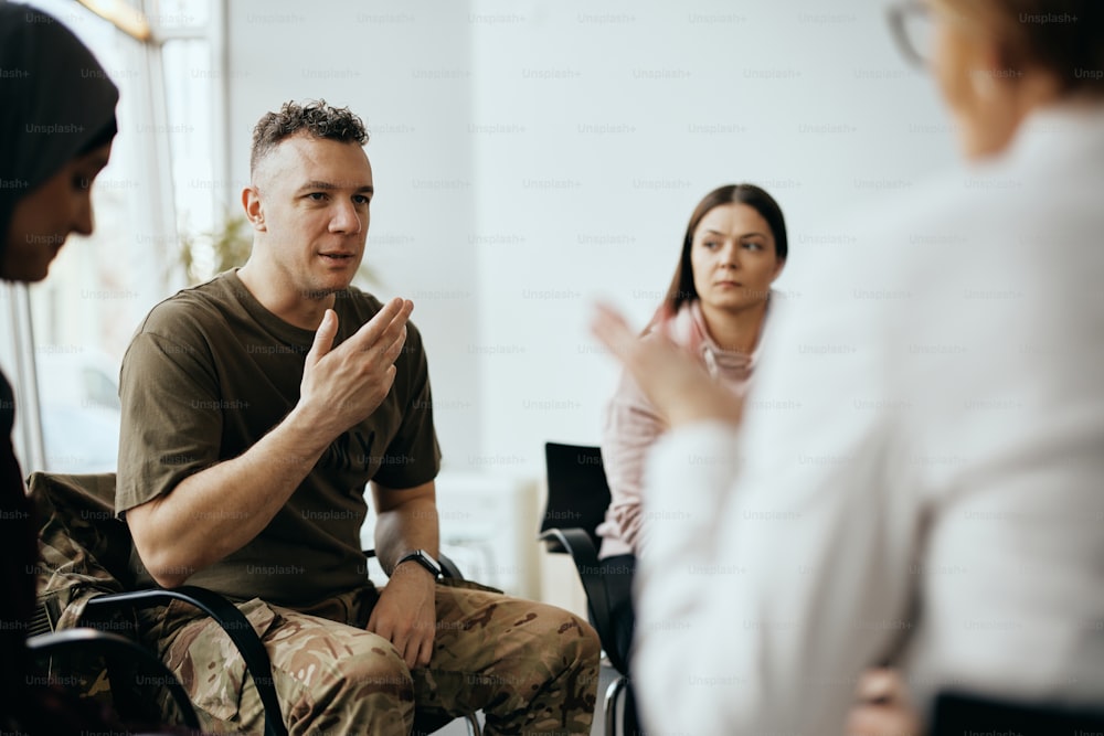 Military man attending group therapy and communicating with other participants and a psychotherapist.