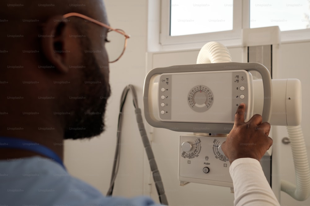 Hand of young African American radiologist pressing button on panel while preparing for medical examination of patients