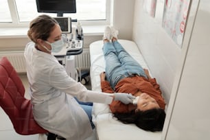 Joven clínico contemporáneo escaneando el cuello de una paciente hispana enferma durante el examen de ultrasonido en clínicas
