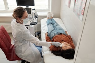 Un jeune clinicien contemporain scanne le cou d’une patiente hispanique malade lors d’un examen échographique dans des cliniques