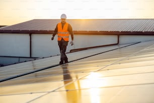 Un riparatore che cammina intorno al tetto e controlla i pannelli solari.