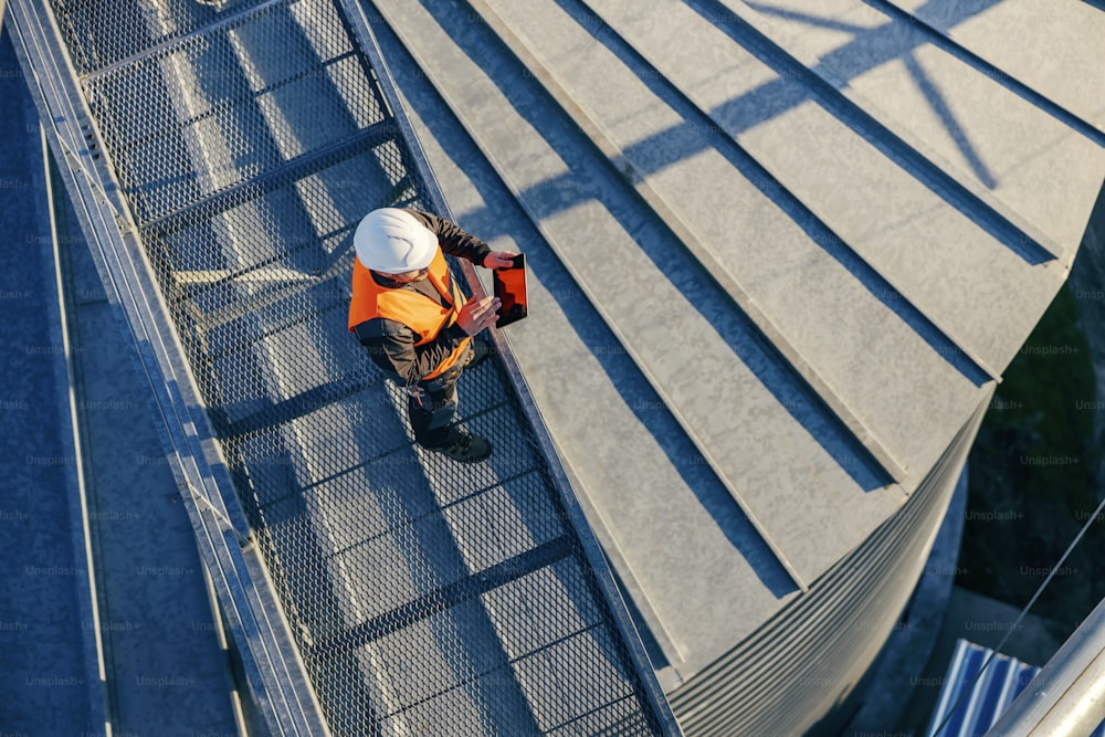 Top view of a worker on silo checking on supply on tablet.