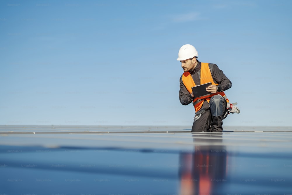 A handyman using tablet for solar panels testing on the roof.