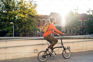 Stock photo of bearded man riding his detachable bike in the street.