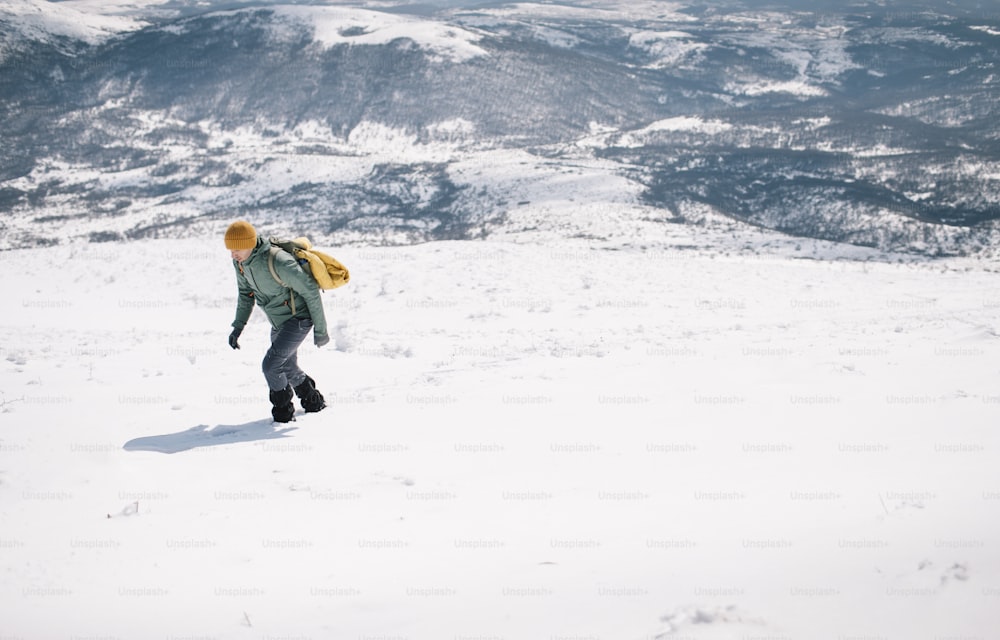 Hiker wearing gaiters climbing mountain in the winter.