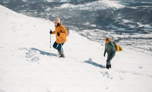 Hiking couple in gaiters climbing snowy mountain.