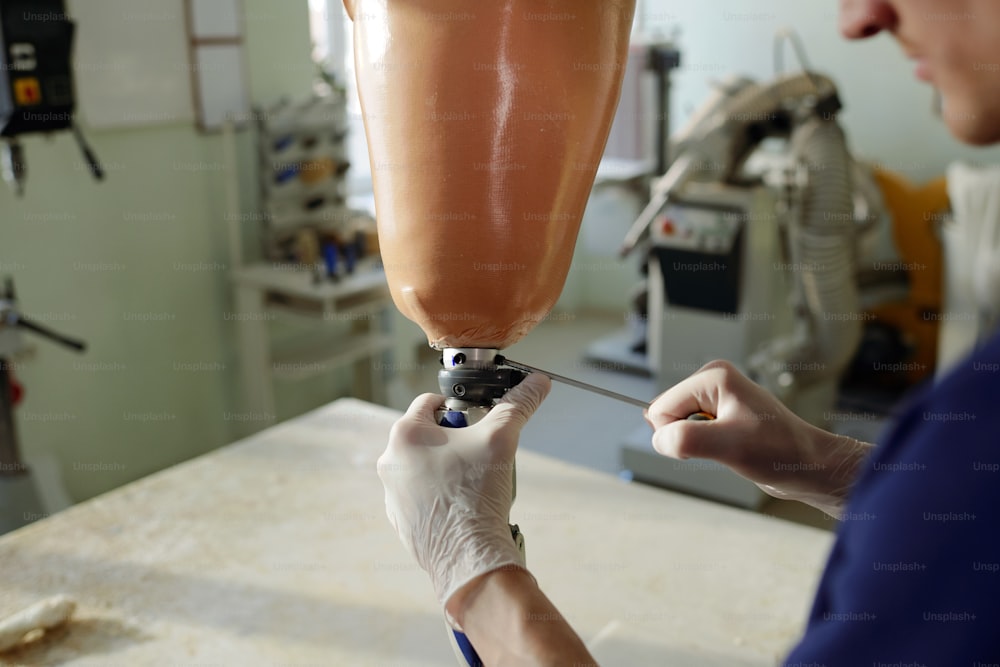 Spezialist der Prothesenproduktion Fabrik Befestigung der Pfanne der Beinprothese mit Schraubendreher während der Montage aller Abschnitte der künstlichen Extremität