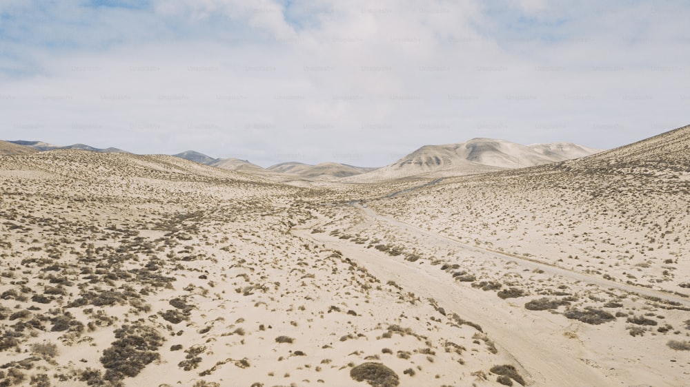 Bellissima destinazione di viaggio panoramica con dune di sabbia e deserto con cielo luminoso e montagne nel paesaggio. Concetto di desertificazione e cambiamento climatico per il riscaldamento globale.