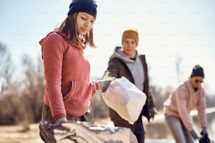 Adolescente con un grupo de personas recogiendo basura mientras limpian el medio ambiente.