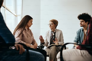 Mature mental health professional communicating with group of people during counseling at community center.