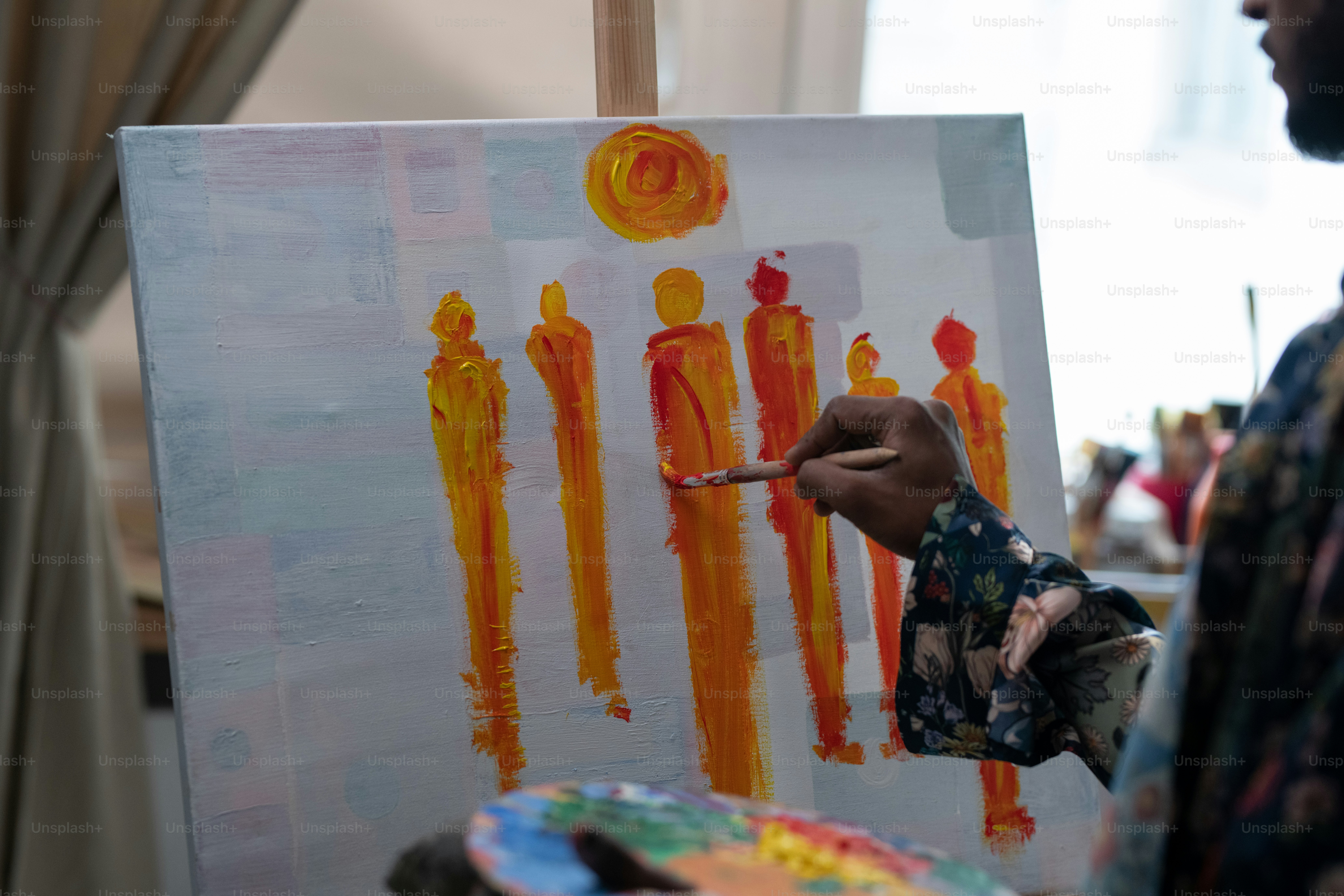 アートスタジオや自宅で作業しながらキャンバスに絵筆とカラーパレットで描く若い現代アーティストの手