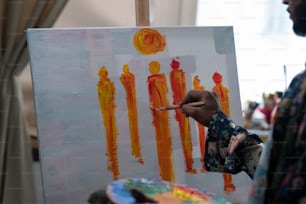 아트 스튜디오나 집에서 작업하는 동안 캔버스에 붓과 컬러 팔레트 그림을 그린 젊은 현대 예술가의 손