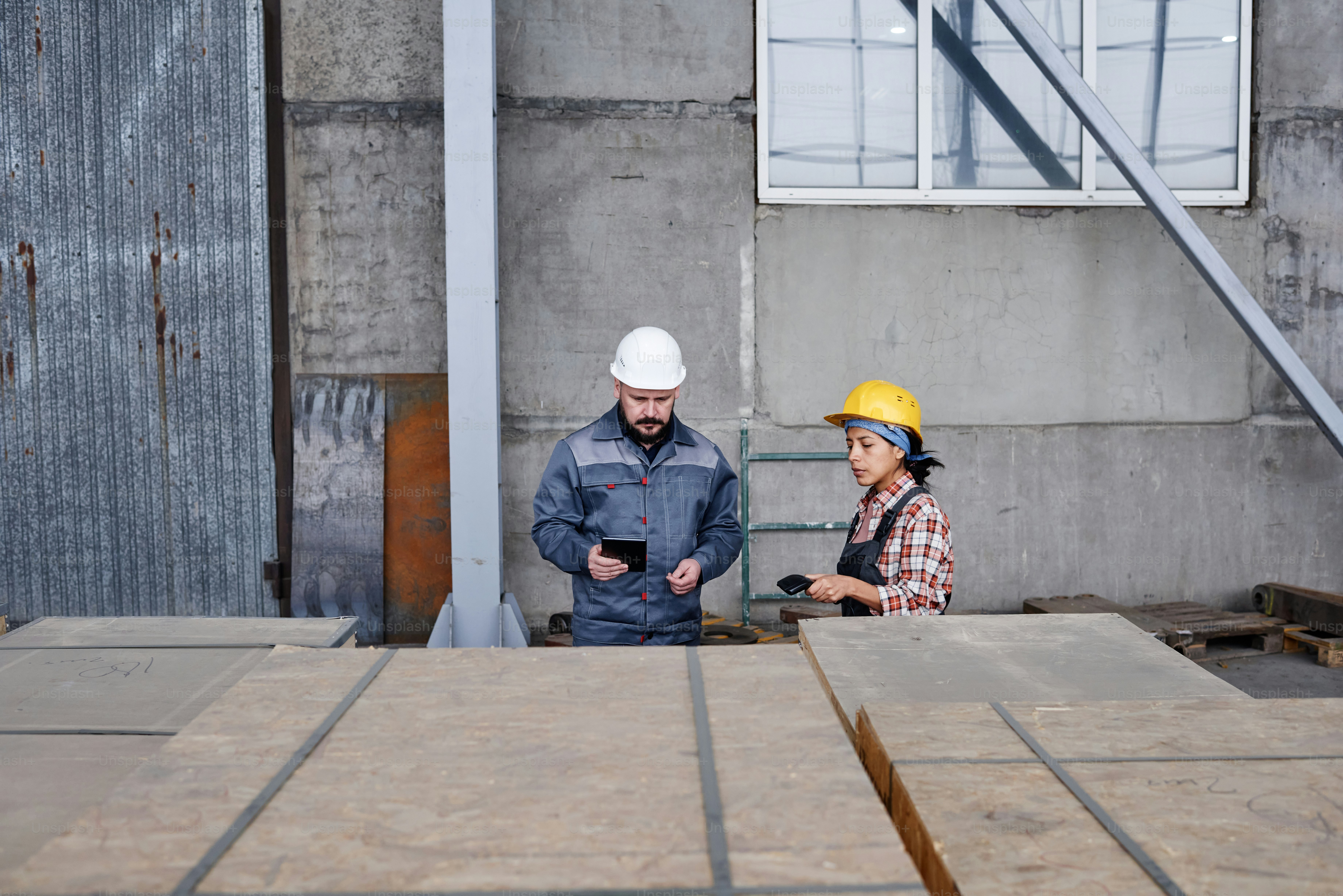 Two workers of distribution warehouse checking barcodes on containers with new spare parts for contemporary industrial machines