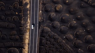 Vehículo de automóvil blanco que viaja y conduce por un camino largo y recto en un lugar volcánico pintoresco. Vista aérea de drones por encima de personas y concepto de viaje. Suelo volcánico de arena negra visto desde la vista vertical