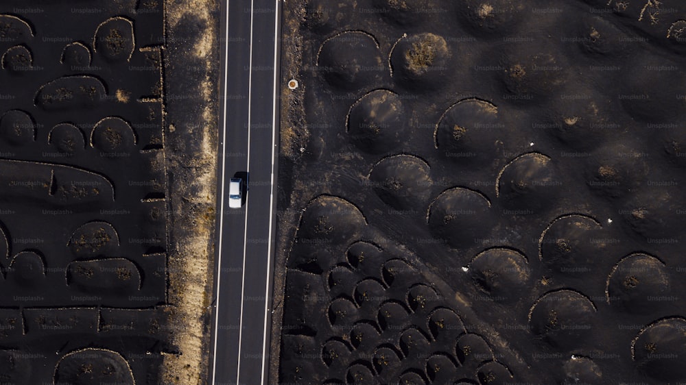 White car vehicle  traveling and driving on a long straight road inscenic volcanic place. Above drone aerial view of people and travel concept. Black sand volcanic ground viewed from vertical view