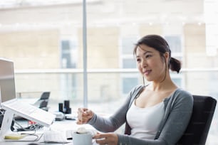 a woman sitting at a desk with a cup of coffee