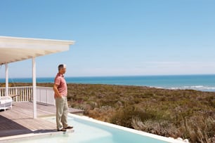 a man standing on a deck next to a swimming pool