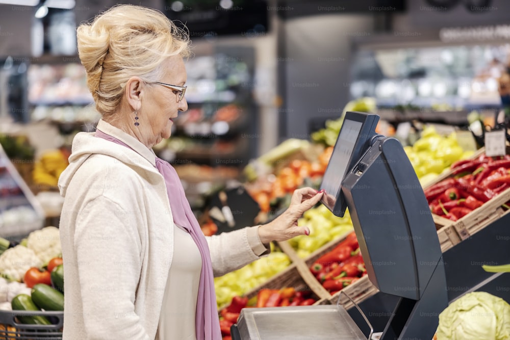 A grandmother measuring groceries on scale at the supermarket.