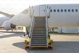 Civil jet aircraft with ladder stairs and airport and other plane on background