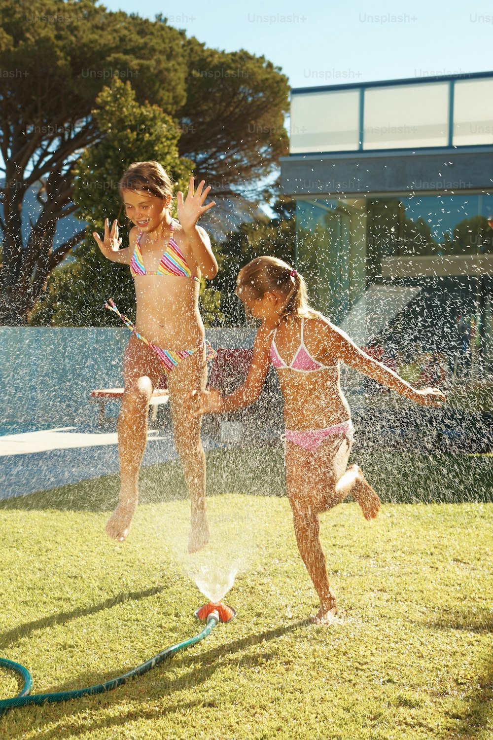 two young girls playing in a sprinkle pool