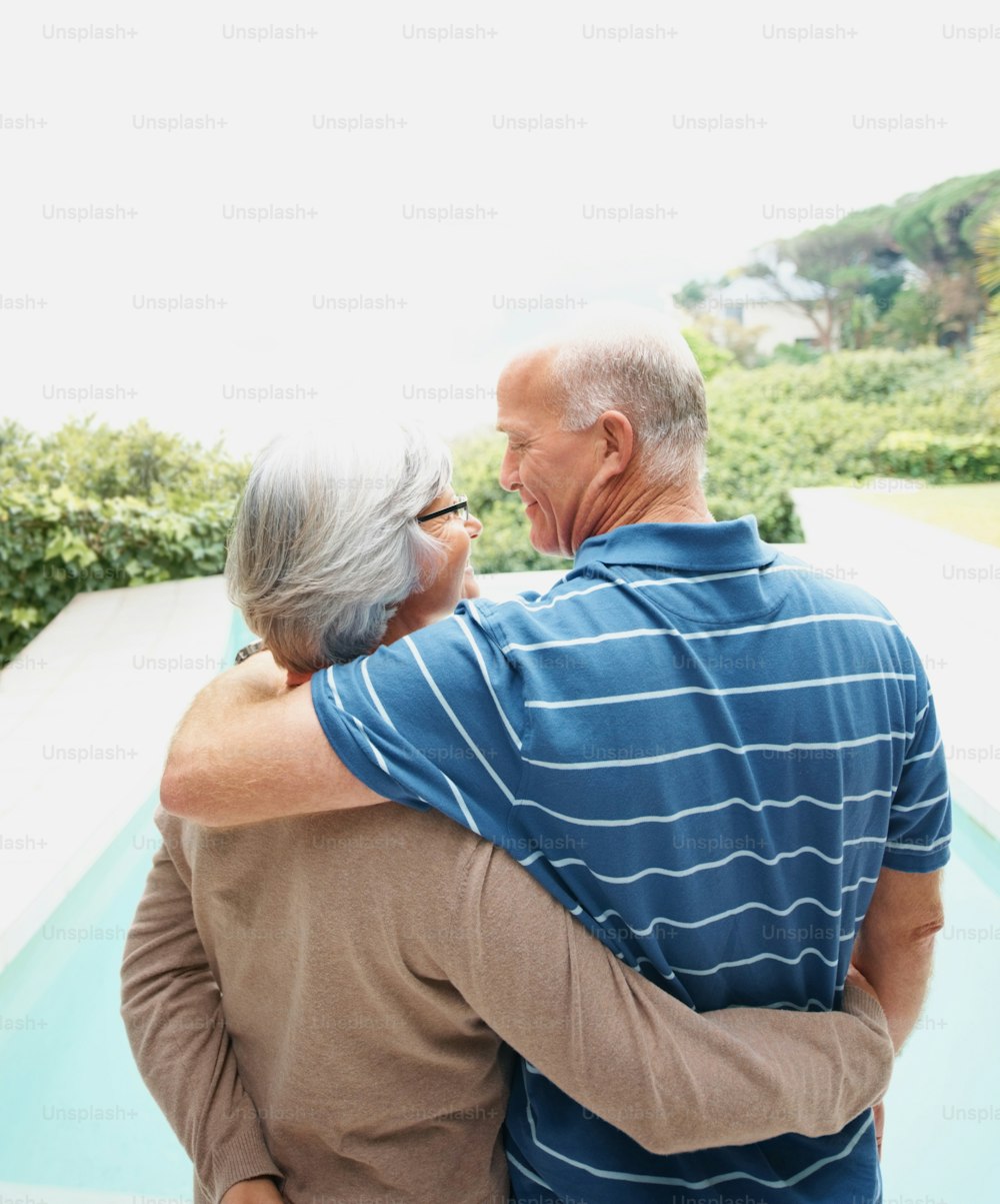 an older couple embracing each other in front of a pool