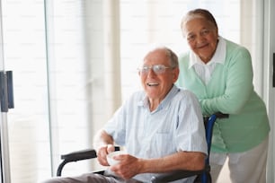 Anciano en silla de ruedas asistido por su esposa