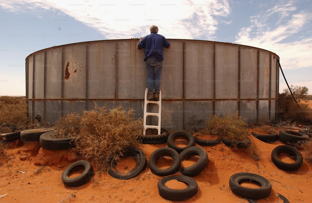 a man standing on a ladder next to a large tank