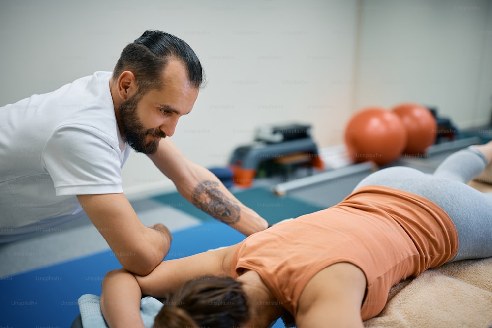 Mulher atlética recebendo massagem esportiva no centro de fisioterapia. O foco está no fisioterapeuta.