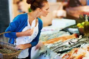Una donna in piedi di fronte a un'esposizione di pesci