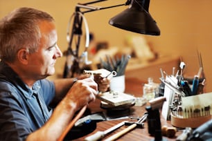 a man sitting at a desk working on a piece of art